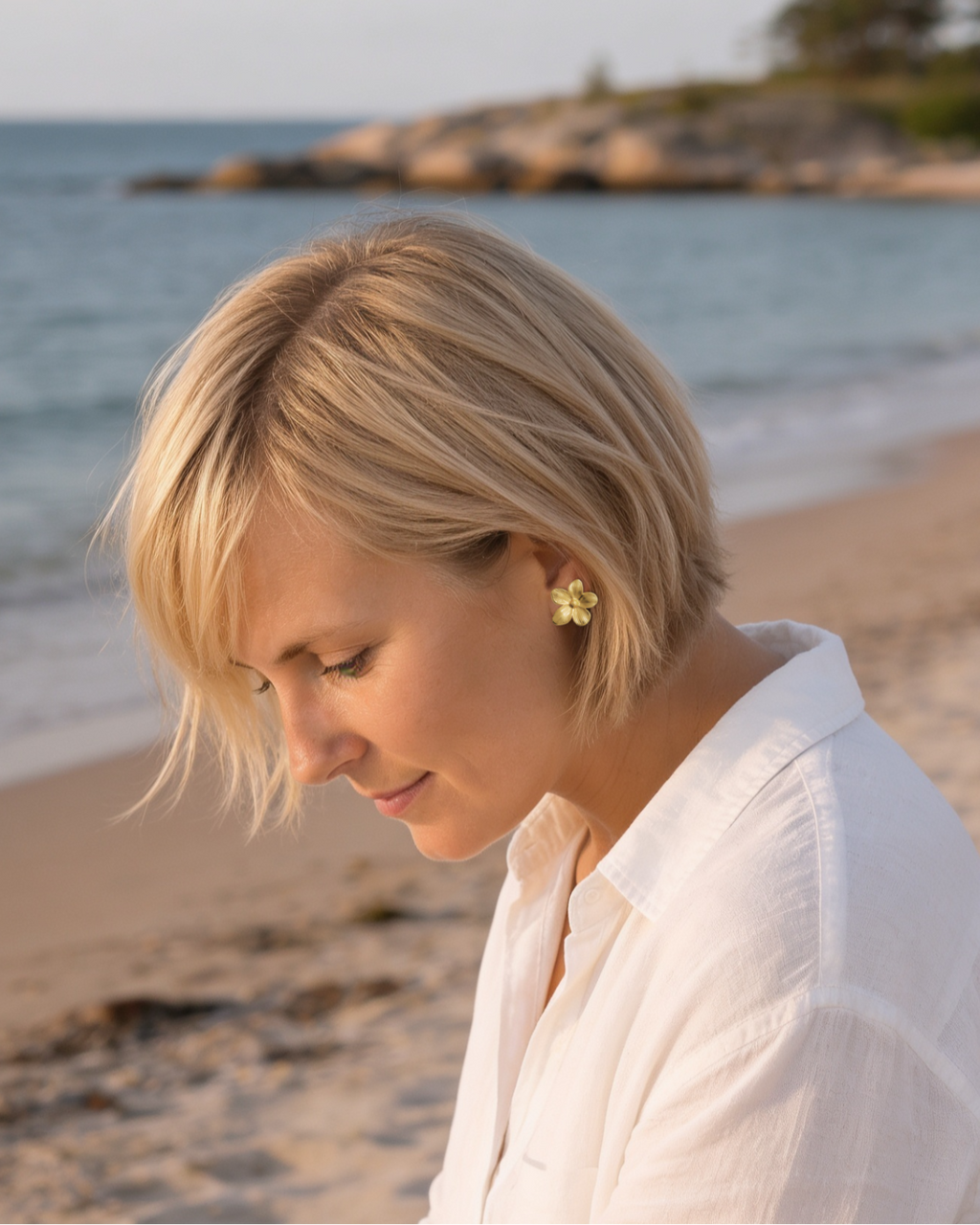 Gold flower stud earrings worn by a woman on Tulliniemi beach in Hanko, Finland.