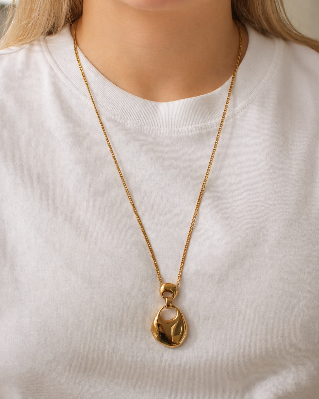 Gold-tone organic drop pendant necklace with a fluid sculptural silhouette worn by a model by HNKO