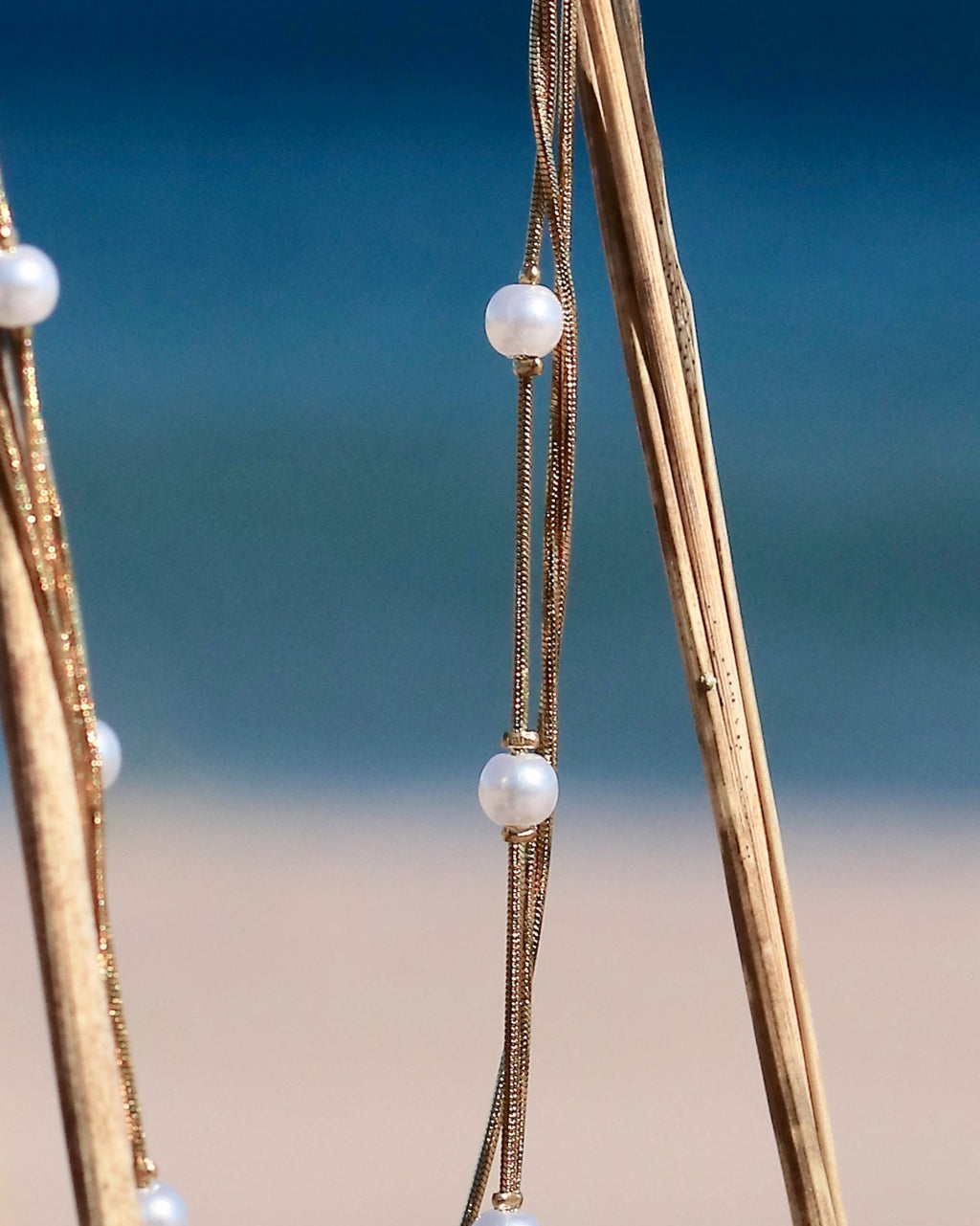 Gold-tone pearl chain necklace with delicate imitation pearls displayed on coastal vegetation in Hanko, Finland