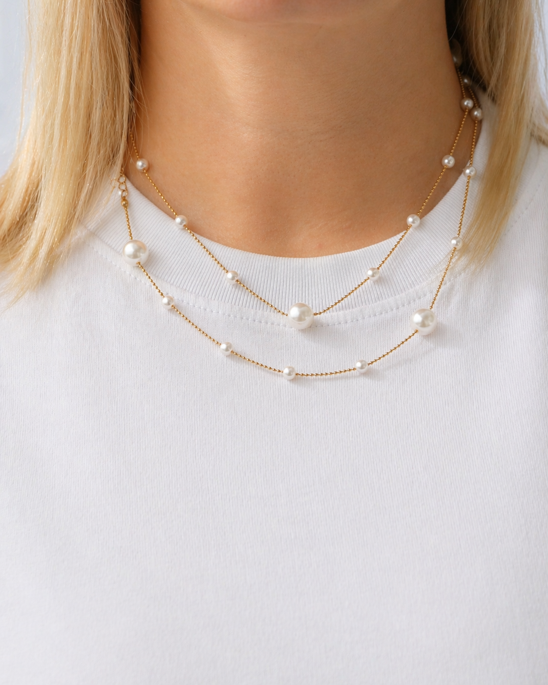Gold-tone pearl chain necklace with delicate imitation pearls styled on a model in a modern coastal-inspired look by HNKO
