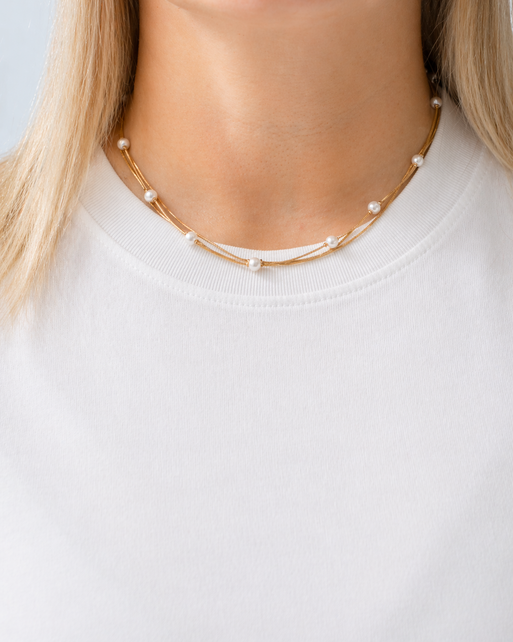 Gold-tone pearl necklace with imitation pearls inspired by Nordic coastal elegance worn by a model by HNKO