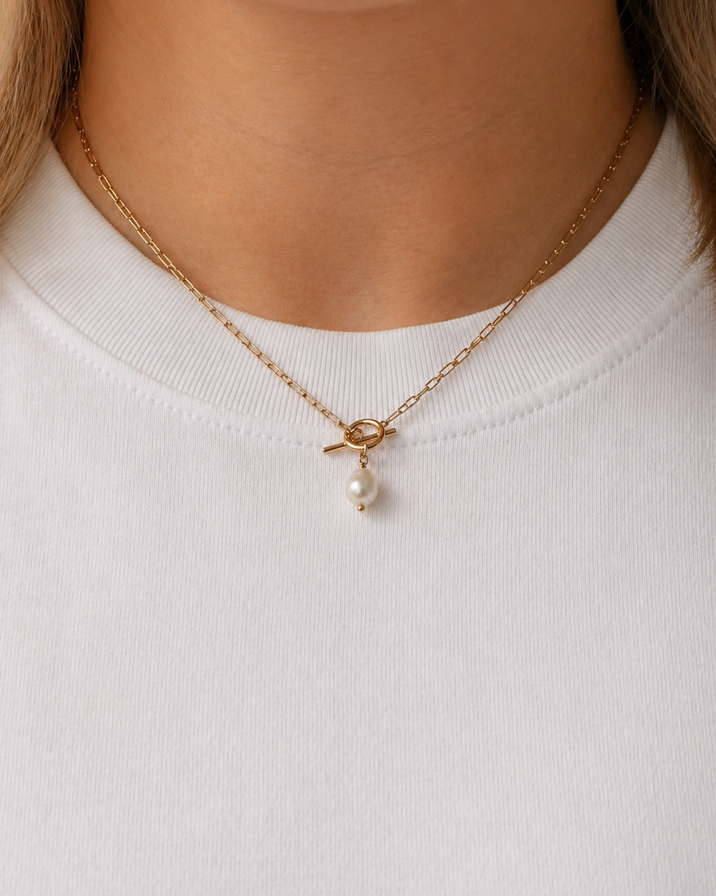 Model wearing a gold toggle necklace with a freshwater pearl pendant by HNKO Finland